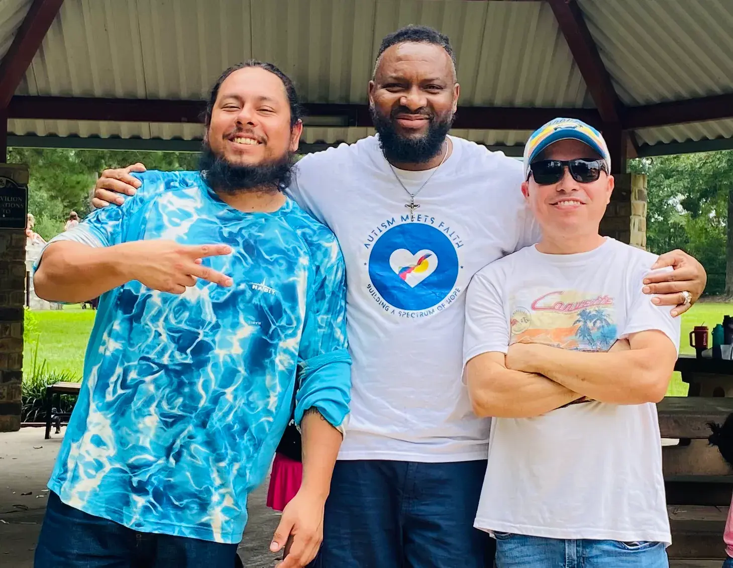 Three community members stand together outdoors in AMF shirts.
