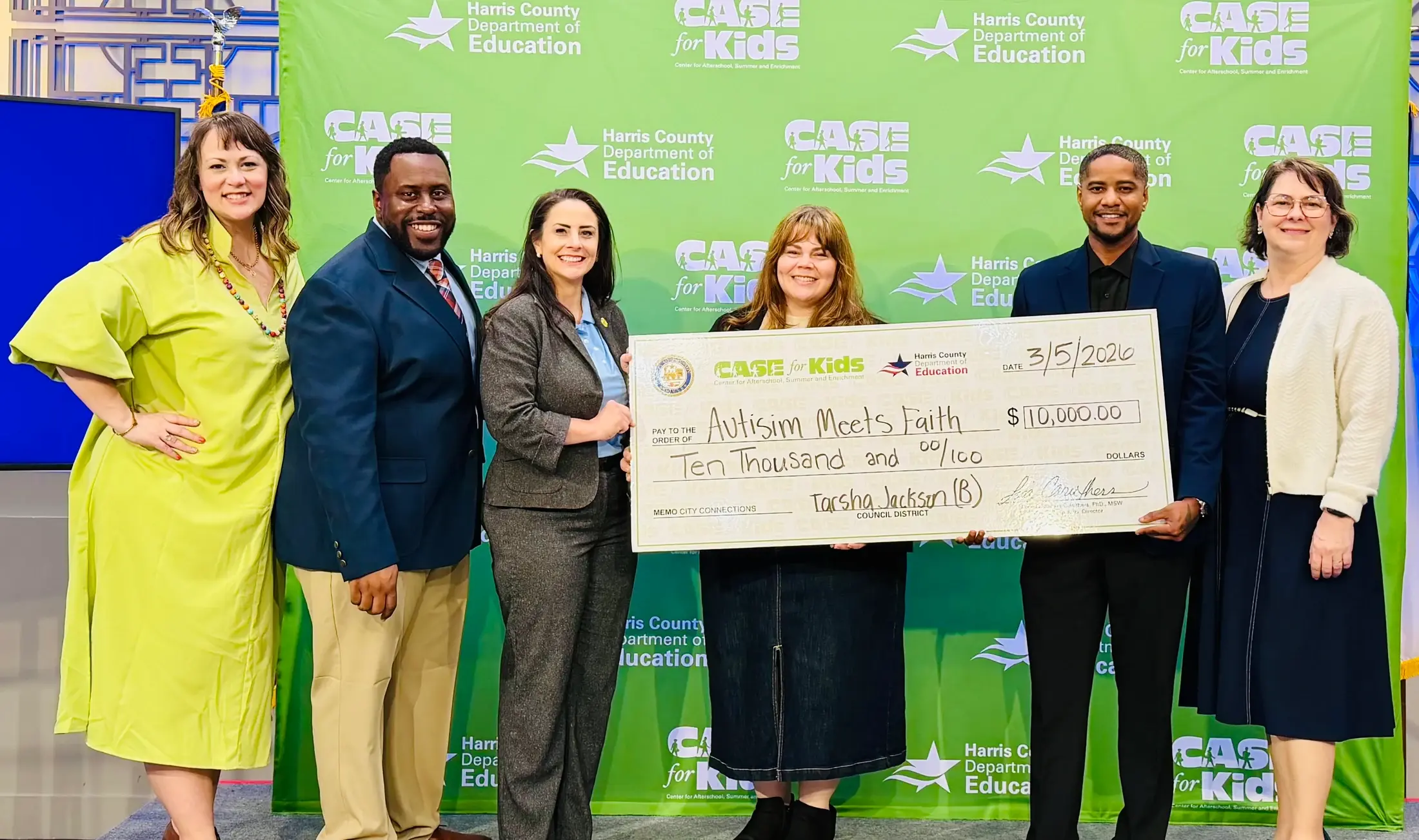 Autism Meets Faith representatives and community leaders hold a large donation check together.