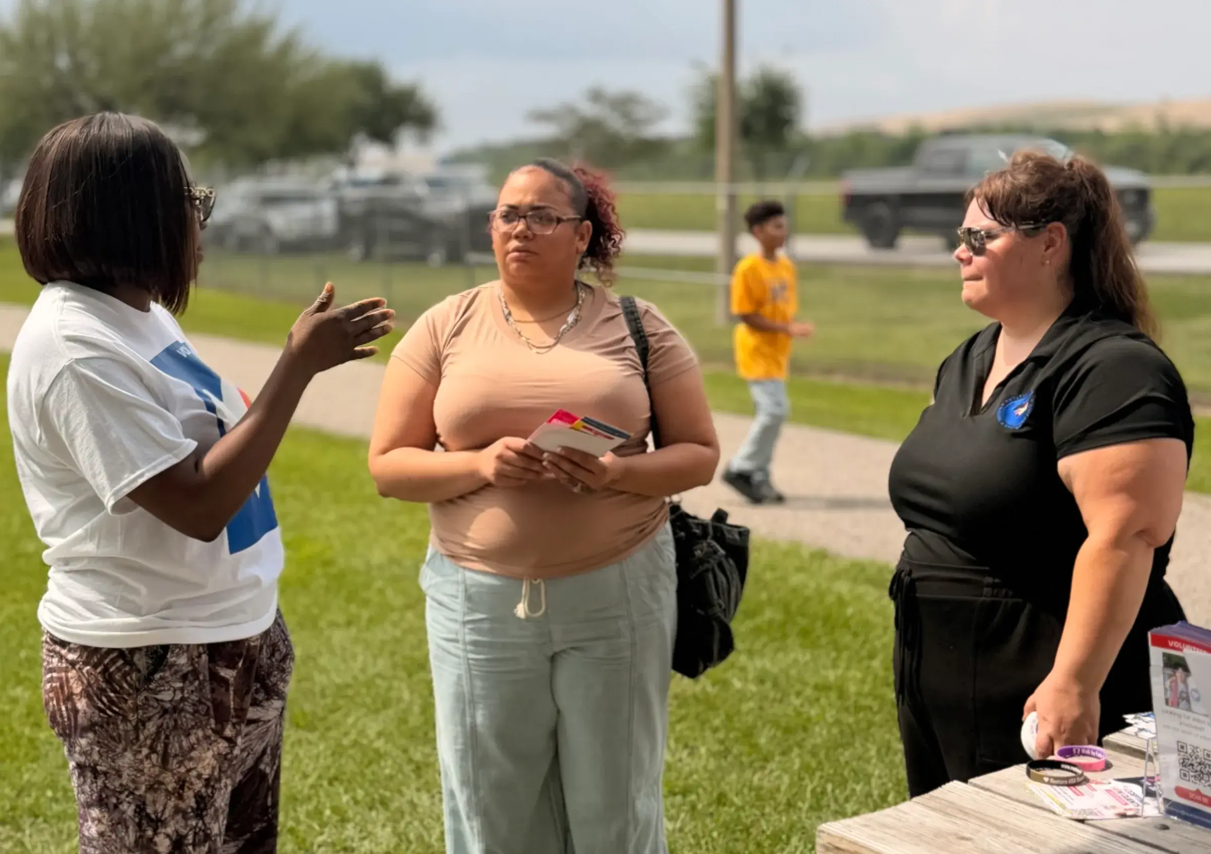 A community member speaks with AMF staff at an outdoor event.