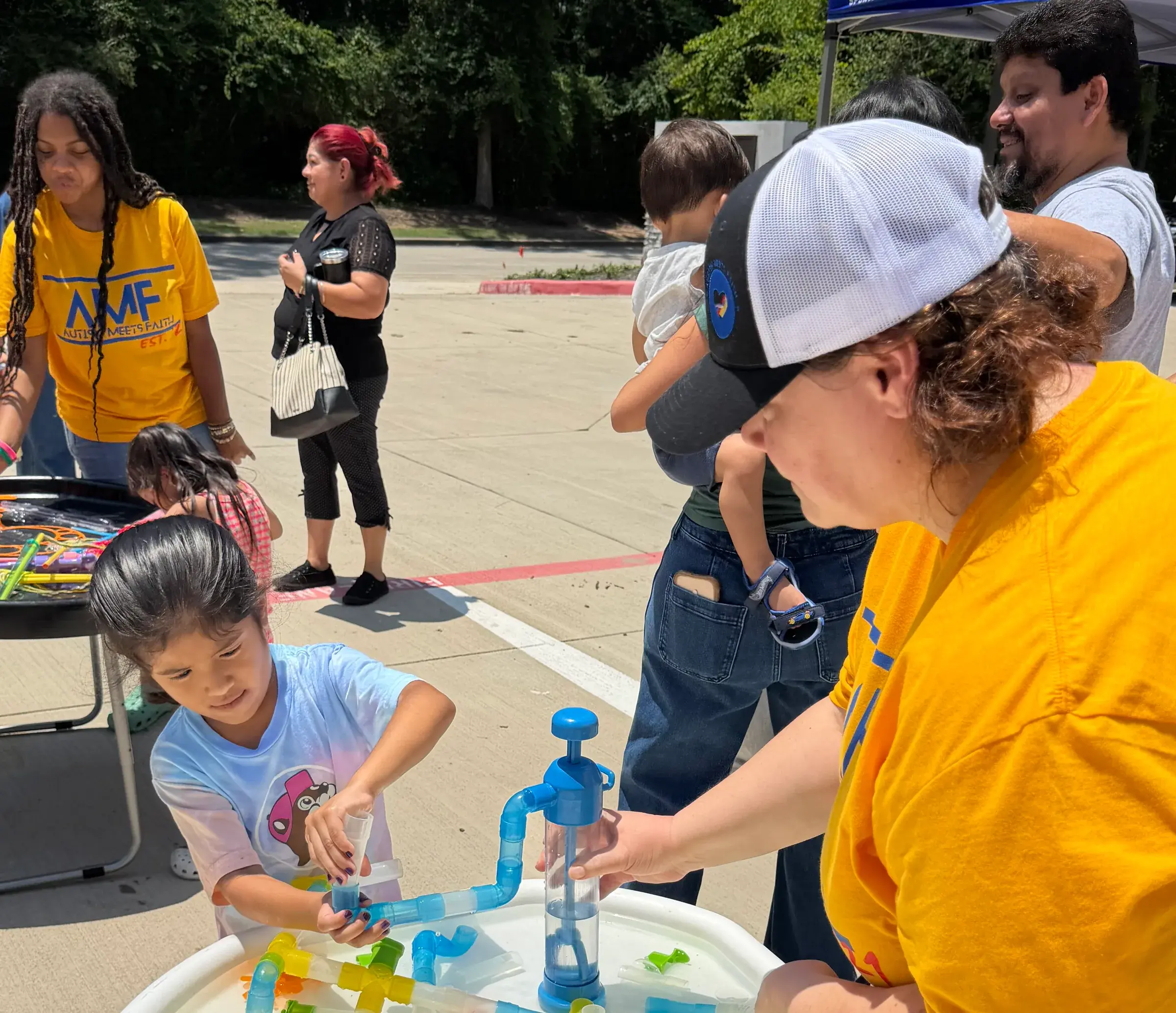 A young child explores a water activity with support at an AMF family event.