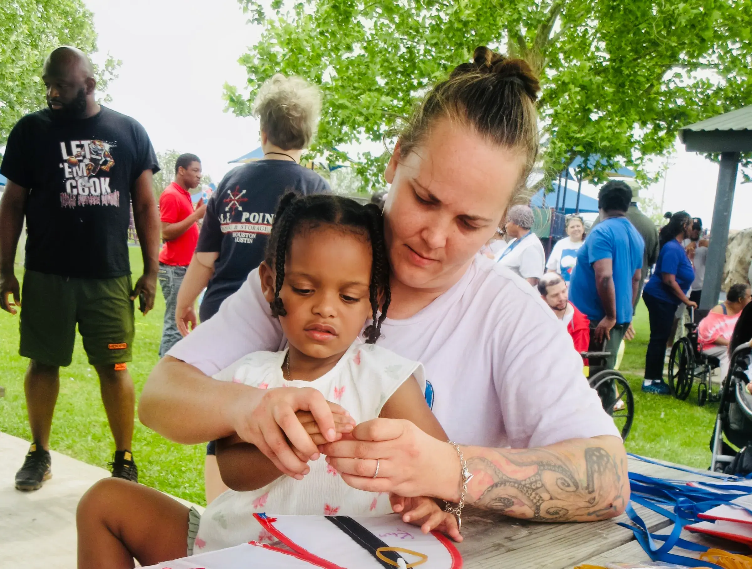 A caregiver helps a young child take part in an activity at a family event.