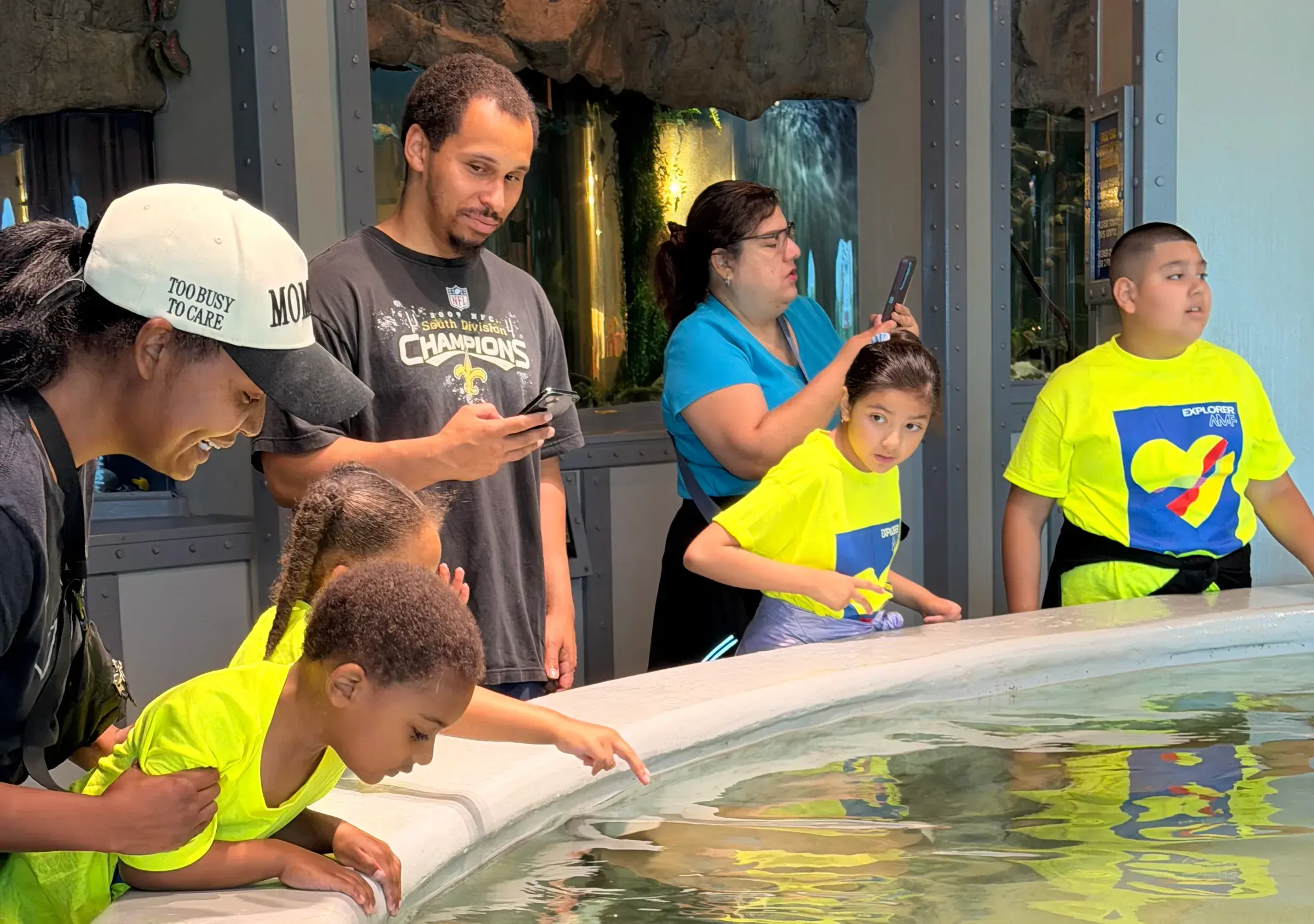 A child reaches toward the water at an aquarium touch tank.