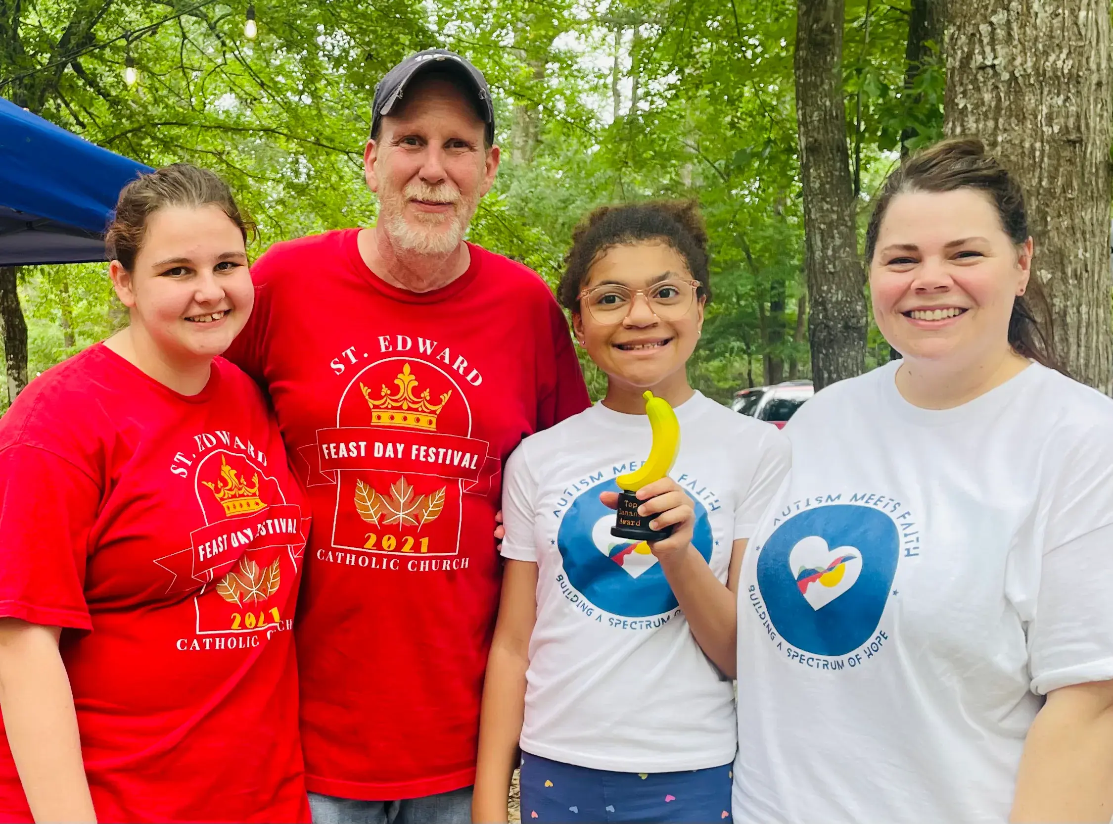 A family and community members stand together at an outdoor event.
