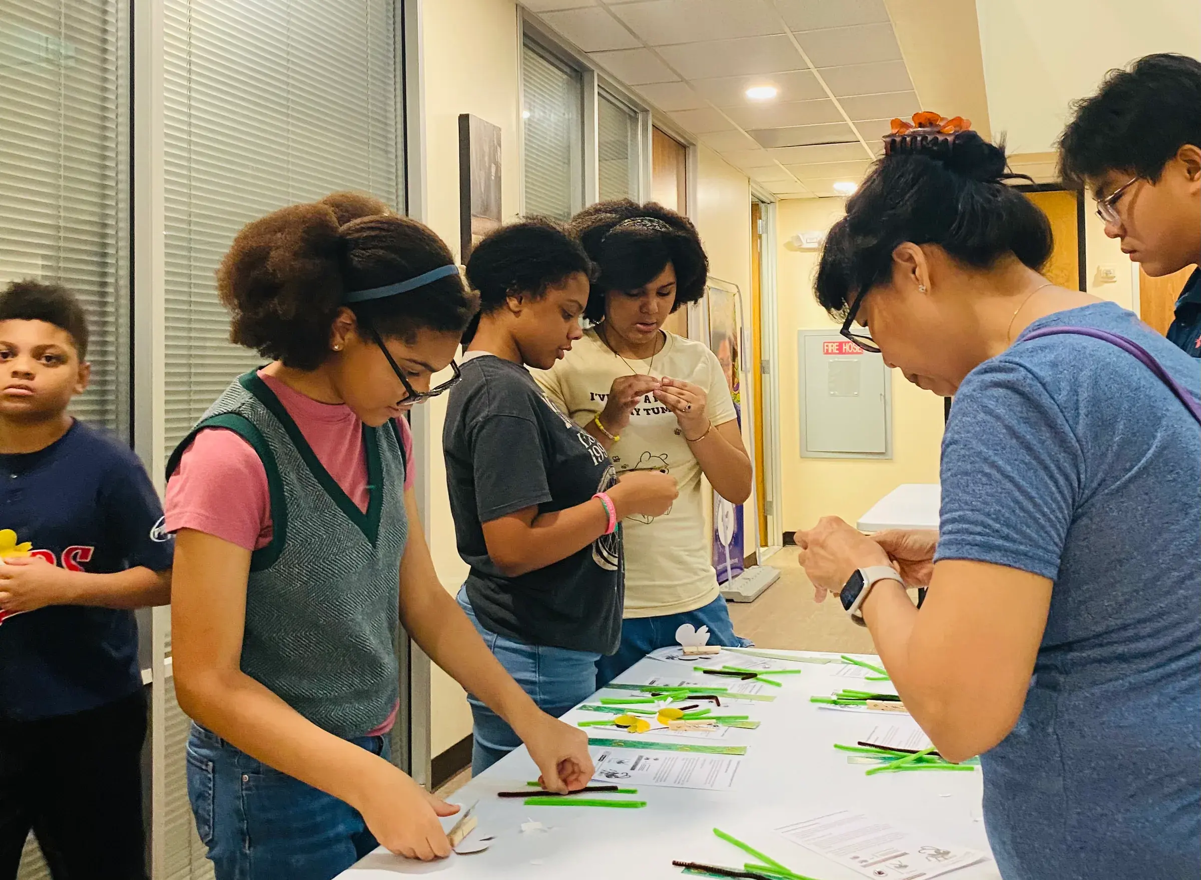 Young people work together on a project at a table with an instructor.