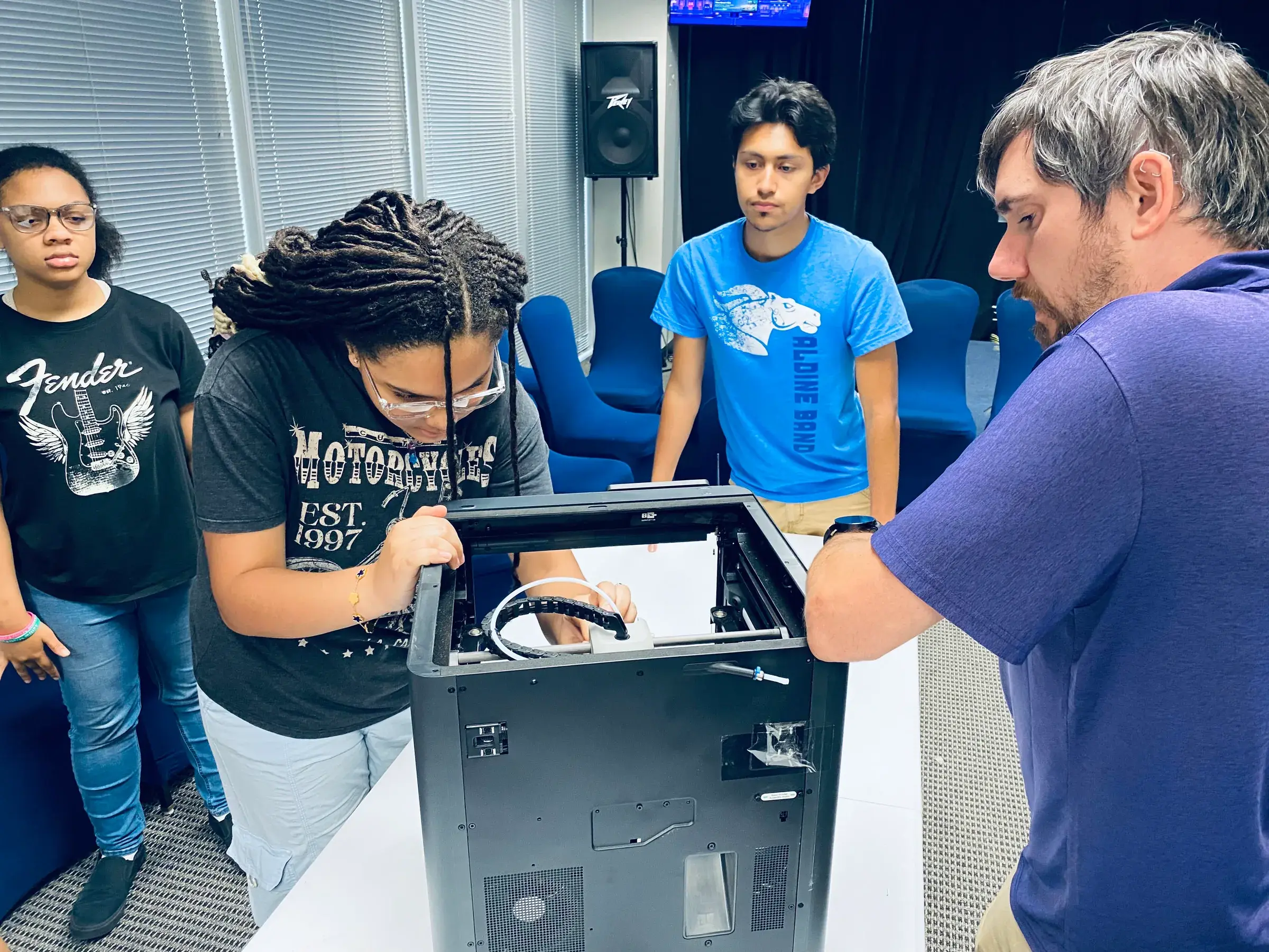 Young people explore a digital fabrication machine with an instructor.